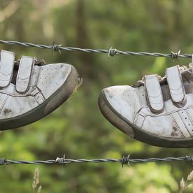 this is an image of an old pair of trainers hanging on a wire fence